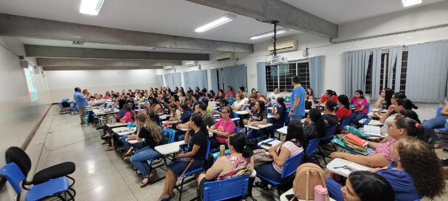 Na foto pode-se ver um auditório com mais de 60 pessoas no público e um professor em frente a essas pessoas. 