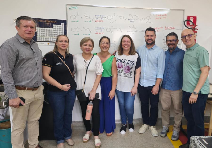 Na foto estão oito pessoas, lado a lado, ao fundo se vê um quadro de sala de aula