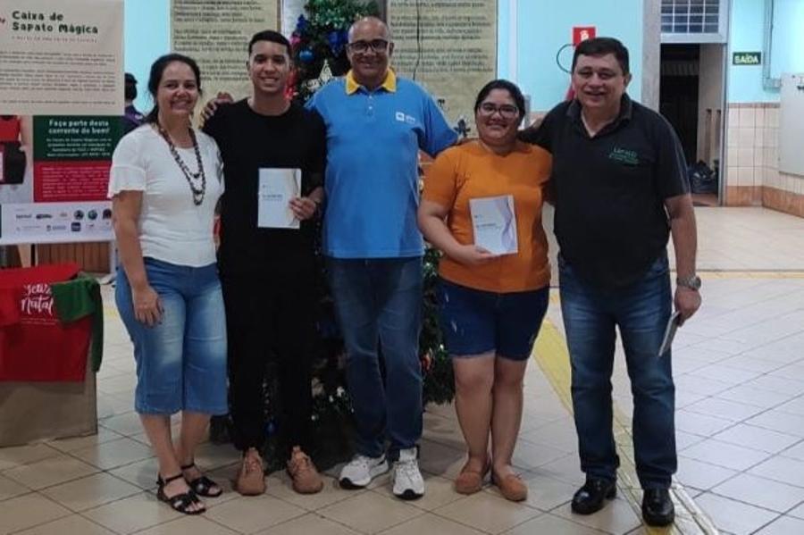 Enrique Duarte Romero entregando os glossários para dois estudantes estrangeiros da FACE. 